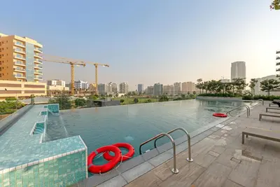 a large swimming pool with a city in the background at Lux 1 Bedroom Apartment in Majan in Dubai