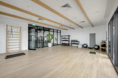 an empty room with a gym with wood floors at Lux 1 Bedroom Apartment in Majan in Dubai