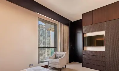 a bedroom with a bed and a chair and a window at Dubai Mall 5 star Free Parking in Dubai