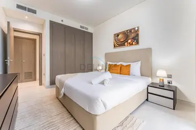 a white bedroom with a large bed and a television at Glimpse of Burj Khalifa 2BR, 15-Minute Drive to Burj Khalifa and Downtown Landmarks, District One Phase III Residences 13, Mohammed Bin Rashid Al Maktoum City by Deluxe Holiday Homes in Dubai