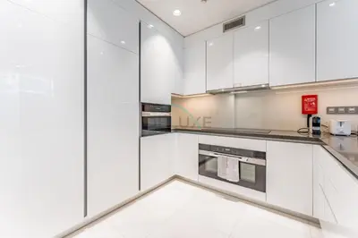 a white kitchen with white cabinets and appliances at Glimpse of Burj Khalifa 2BR, 15-Minute Drive to Burj Khalifa and Downtown Landmarks, District One Phase III Residences 13, Mohammed Bin Rashid Al Maktoum City by Deluxe Holiday Homes in Dubai
