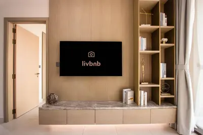 a living room with a tv on a wall at Luxury 1BR High Floor Rooftop Pool Access in Dubai