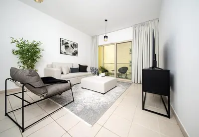 a white living room with a couch and a table at Stunning 1 Bed in Al Dhafra 2 The Greens in Dubai