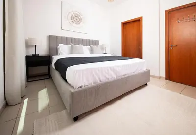 a bedroom with a large bed and a wooden door at Stunning 1 Bed in Al Dhafra 2 The Greens in Dubai