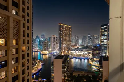 a view of a city skyline at night at GuestReady | 2BR | Stunning Canal View, JBR in Dubai