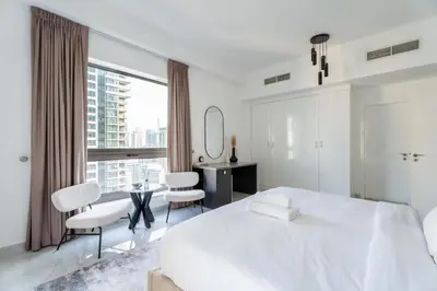 a white bedroom with a large bed and a desk at GuestReady | 2BR | Stunning Canal View, JBR in Dubai