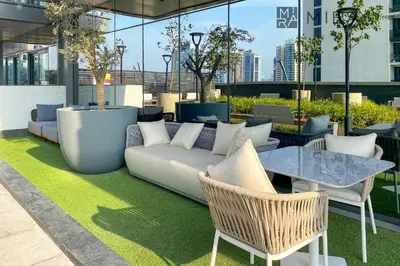 a living room with a couch and a table and chairs at Mira Holiday Homes - High View 2 Bed Oasis at Nobles Tower with Sauna in Dubai