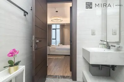 a bathroom with a sink and a mirror and a bed at Mira Holiday Homes - High View 2 Bed Oasis at Nobles Tower with Sauna in Dubai