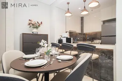 a dining room with a table and chairs at Mira Holiday Homes - High View 2 Bed Oasis at Nobles Tower with Sauna in Dubai