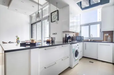 a kitchen with white cabinets and a washer and dryer at Frank Porter - Dec Towers 1 in Dubai