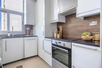 a white kitchen with white cabinets and appliances at Frank Porter - Dec Towers 1 in Dubai