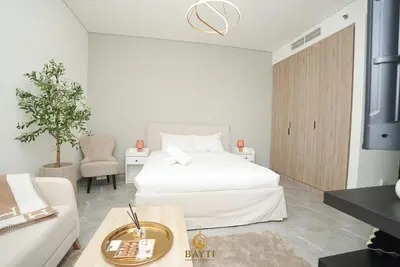 a white bedroom with a bed and a couch at Evasion Moderne a Business Bay vue sur le canal in Dubai