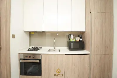 a kitchen with white cabinets and a sink and a microwave at Evasion Moderne a Business Bay vue sur le canal in Dubai