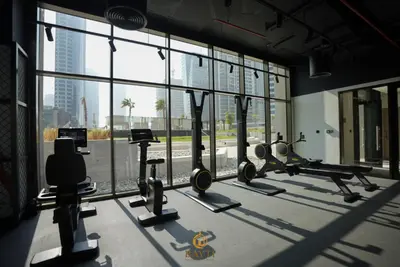 a gym with treadmills and machines in a room with windows at Evasion Moderne a Business Bay vue sur le canal in Dubai