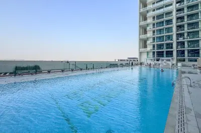 a large swimming pool in front of a building at Minimalist Studio in Binghatti Azure in Dubai