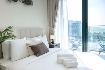 a white bed with white pillows and a large window at Azizi Riviera 5, Meydan Close to Downtown - Onelink in Dubai