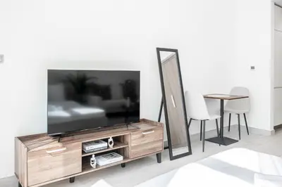 a living room with a television on a wooden entertainment center at Azizi Riviera 5, Meydan Close to Downtown - Onelink in Dubai