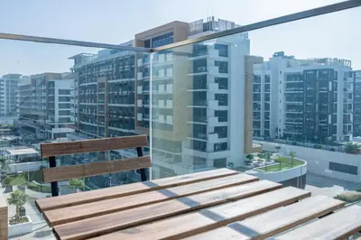 a wooden bench on a balcony with buildings at Azizi Riviera 5, Meydan Close to Downtown - Onelink in Dubai