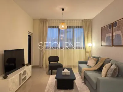a living room with a blue couch and a tv at Cozy & Bright 1BR La Riviera Estate A in Dubai