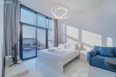 a white room with a bed and a blue couch at O2 Tower JVC, Cozy Home, Peaceful Studio Apartment in Dubai