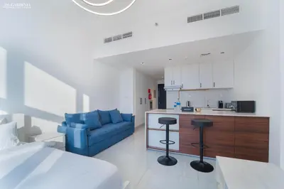 a bedroom with a blue couch and a kitchen at O2 Tower JVC, Cozy Home, Peaceful Studio Apartment in Dubai