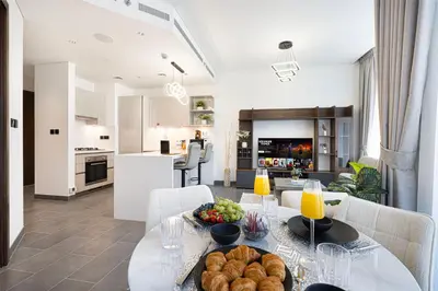 a kitchen and a living room with a table with food at Luxurious Crest Tower Suites By Hostiva- Burj View in Dubai