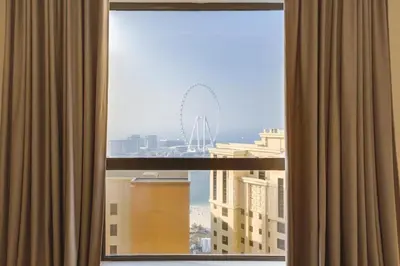 a view of a ferris wheel from a hotel room window at 2 Bedroom Apartment, JBR Beach with Dubai Eye View in Dubai