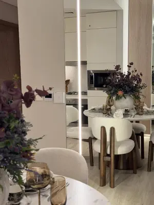 a living room with a table and chairs and a kitchen at Palace Residences, Lux 1BR Apartment, Lagoon View in Dubai