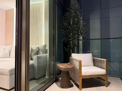 a chair and a stool in a room with a bedroom at Palace Residences, Lux 1BR Apartment, Lagoon View in Dubai