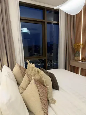 a bedroom with a bed with pillows and a window at Palace Residences, Lux 1BR Apartment, Lagoon View in Dubai