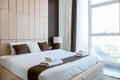 a bedroom with a large white bed with towels on it at Gemz by Danube with Private Pool - Onelink in Dubai