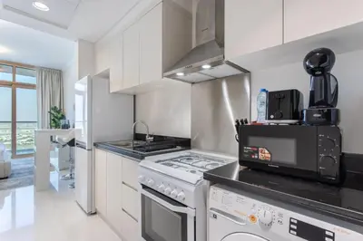 a kitchen with white cabinets and a stove top oven at Sky-High Luxury Studio Overlooking Trump Golf Club-Carson A, DAMAC Hills, Dubai in Dubai
