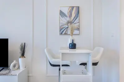 a white table with two chairs and a vase on it at Sky-High Luxury Studio Overlooking Trump Golf Club-Carson A, DAMAC Hills, Dubai in Dubai