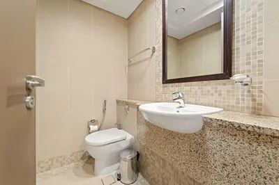 a bathroom with a toilet and a sink and a mirror at Silkhaus Deluxe 1BR Stay in Sky gardens in DIFC in Dubai