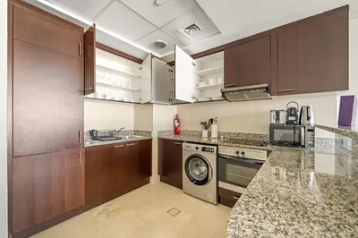a kitchen with wooden cabinets and a washing machine at Silkhaus Deluxe 1BR Stay in Sky gardens in DIFC in Dubai