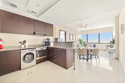 a kitchen with a washing machine and a dining room at Silkhaus Deluxe 1BR Stay in Sky gardens in DIFC in Dubai