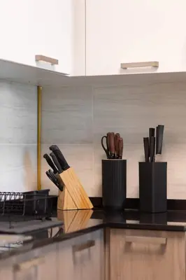 a kitchen with two containers of knives on a counter at Bright & Modern 1BR La Rivera Apartments, JVC in Dubai