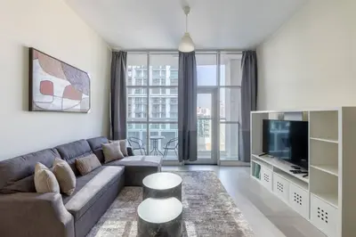 a living room with a couch and a tv at Bright & Modern 1BR La Rivera Apartments, JVC in Dubai