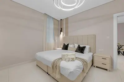 a white bedroom with a large bed and a chandelier at Lavish & Cozy 1BR Apt in the heart of Business Bay in Dubai