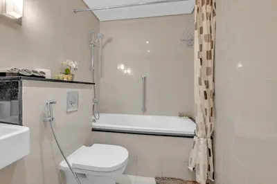a white bathroom with a toilet and a bath tub at Lavish & Cozy 1BR Apt in the heart of Business Bay in Dubai