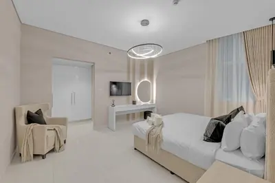 a white bedroom with a bed and a chair at Lavish & Cozy 1BR Apt in the heart of Business Bay in Dubai