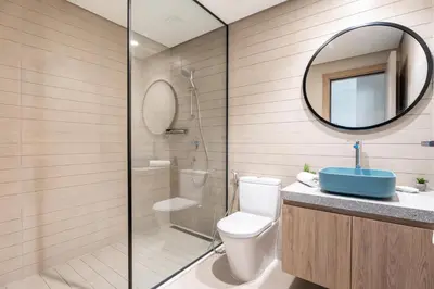 a bathroom with a shower and a toilet and a mirror at GuestReady - 2BR l Stunning Canal View in Dubai