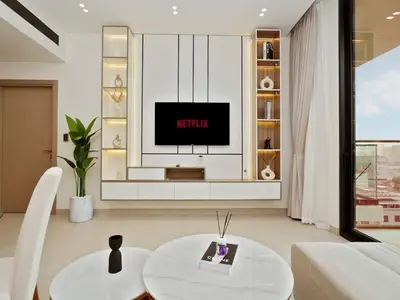 a living room with a tv and a table at Bright Apartment in JVC with Pool in Dubai