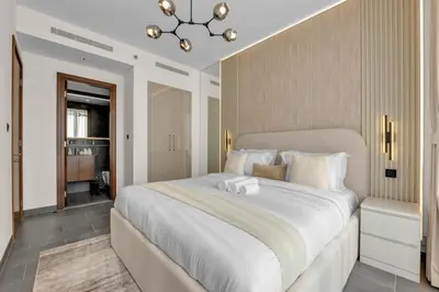 a bedroom with a large white bed with a chandelier at Waves - Modern & Cozy 1BR Apt Close to Down Town Dubai in Dubai