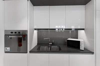a white kitchen with a sink and a microwave at Bluewaters Residences 1BR Prime Sea and Ain View in Dubai