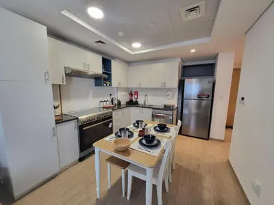 a kitchen with a table and a kitchen with white cabinets at Bright 2BR Apartment 5-Min Walk to Metro & Mall 1124 in Dubai