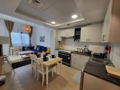 a kitchen and living room with a table and chairs at Bright 2BR Apartment 5-Min Walk to Metro & Mall 1124 in Dubai