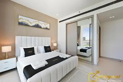 a bedroom with a large white bed and a balcony at Bright 1BR Apartment in Binghatti Phoenix High-Floor Views in Dubai