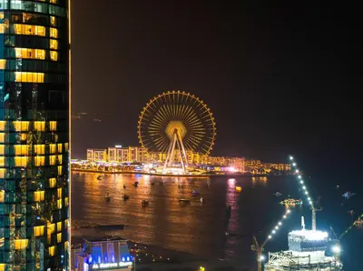 a large ferris wheel on the water at night at Oceanview Palmview Dubai Eye Ain Marina 2BHK in Dubai