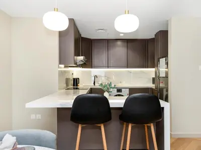 a kitchen with two black chairs at a counter at Oceanview Palmview Dubai Eye Ain Marina 2BHK in Dubai
